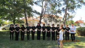 Танцьорите на клуб „Нашенци“ – Русе на поляната преди излизането на сцената, с най-малката нашенка, фолклорен фестивал „Сандрово пее и танцува“, с. Сандрово, 01.09.2012